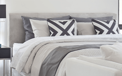 Modern bed with geometric pillows and a gray and white color scheme