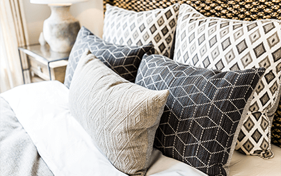 A stylish bed with geometric-patterned pillows in monochrome and neutral tones.