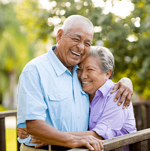 Elderly couple hugging and smiling on a sunny day outdoors
