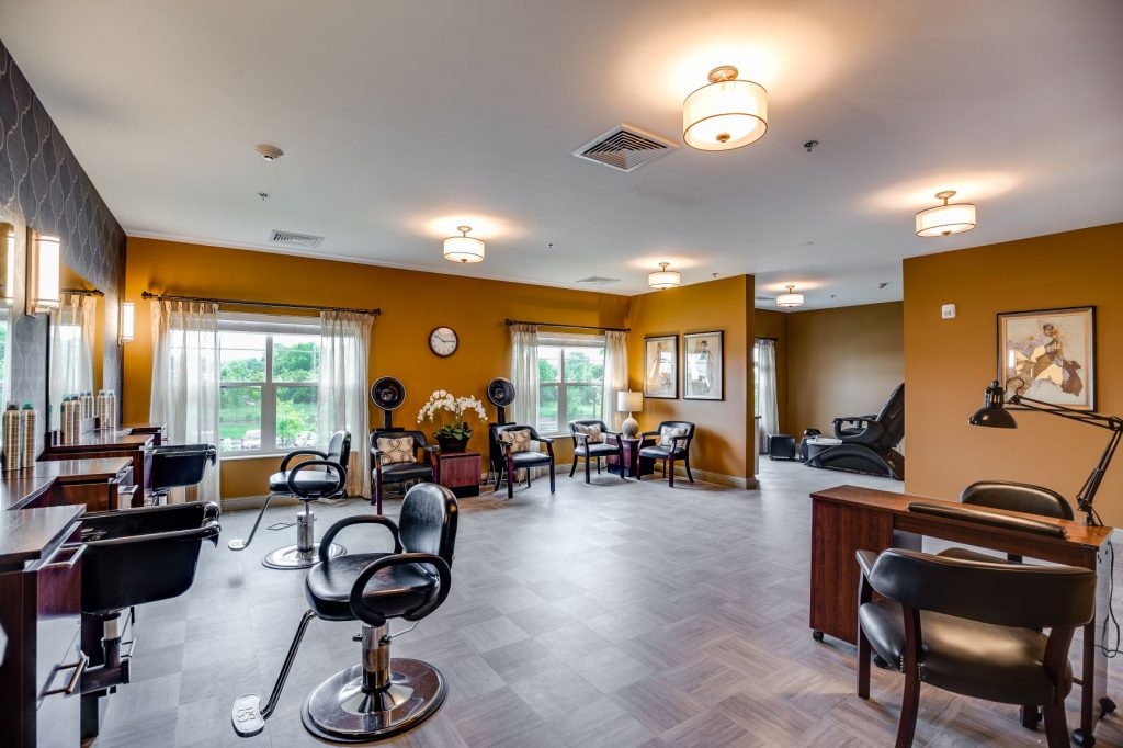 Modern salon with yellow walls, styling chairs, hair washing stations, and waiting area with windows.